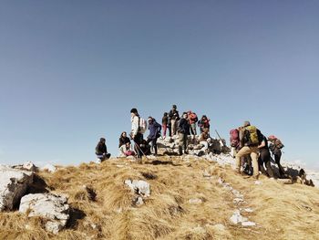 Low angle view of hikers on mountain against sky