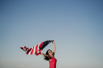 Full length of young woman against blue sky