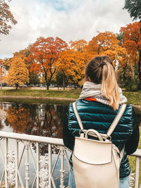 Rear view of woman with umbrella against sky during autumn