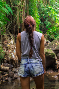 Rear view of woman standing in forest