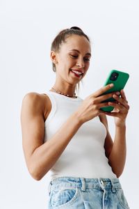 Young woman holding mobile phone against white background