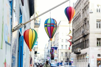 Low angle view of multi colored umbrellas hanging on street amidst buildings