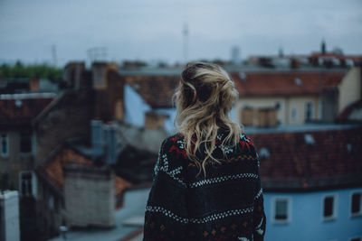 Rear view of woman standing against houses in city