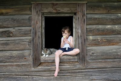 Full length portrait of cute girl sitting on wood