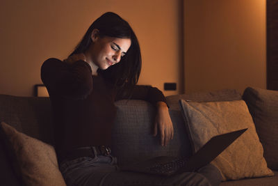 Young woman sitting on sofa at home