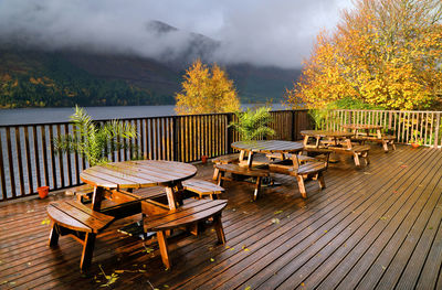 Chairs and tables by lake against sky