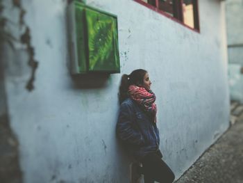 Close-up of girl leaning against building