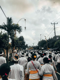 Rear view of people on street in city against sky