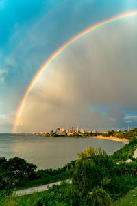 Scenic view of rainbow over sea against cloudy sky during sunset