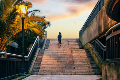 Rear view of man walking on staircase