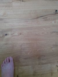 Close-up of hand on wooden floor