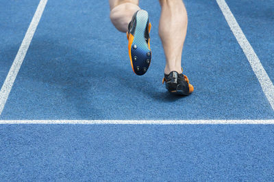 Low section of male athlete running on track