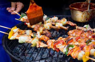 Close-up of person preparing food on barbecue grill