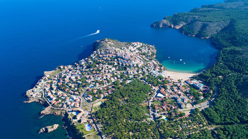 High angle view of cityscape by sea against blue sky
