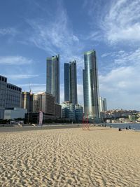 Modern buildings at beach against cloudy sky