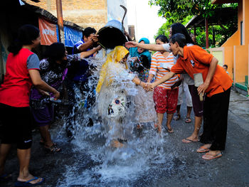 People throwing water on woman at street