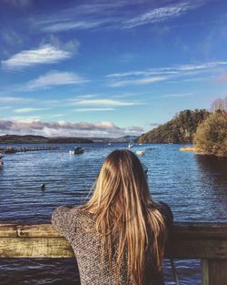 Rear view of woman looking at lake against sky