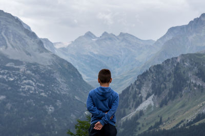 Rear view of man looking at mountains against sky