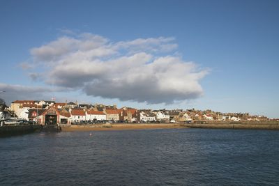 Buildings by sea against sky