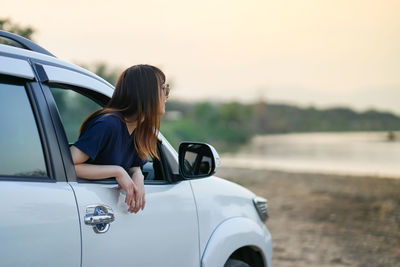 Rear view of woman on car against sky