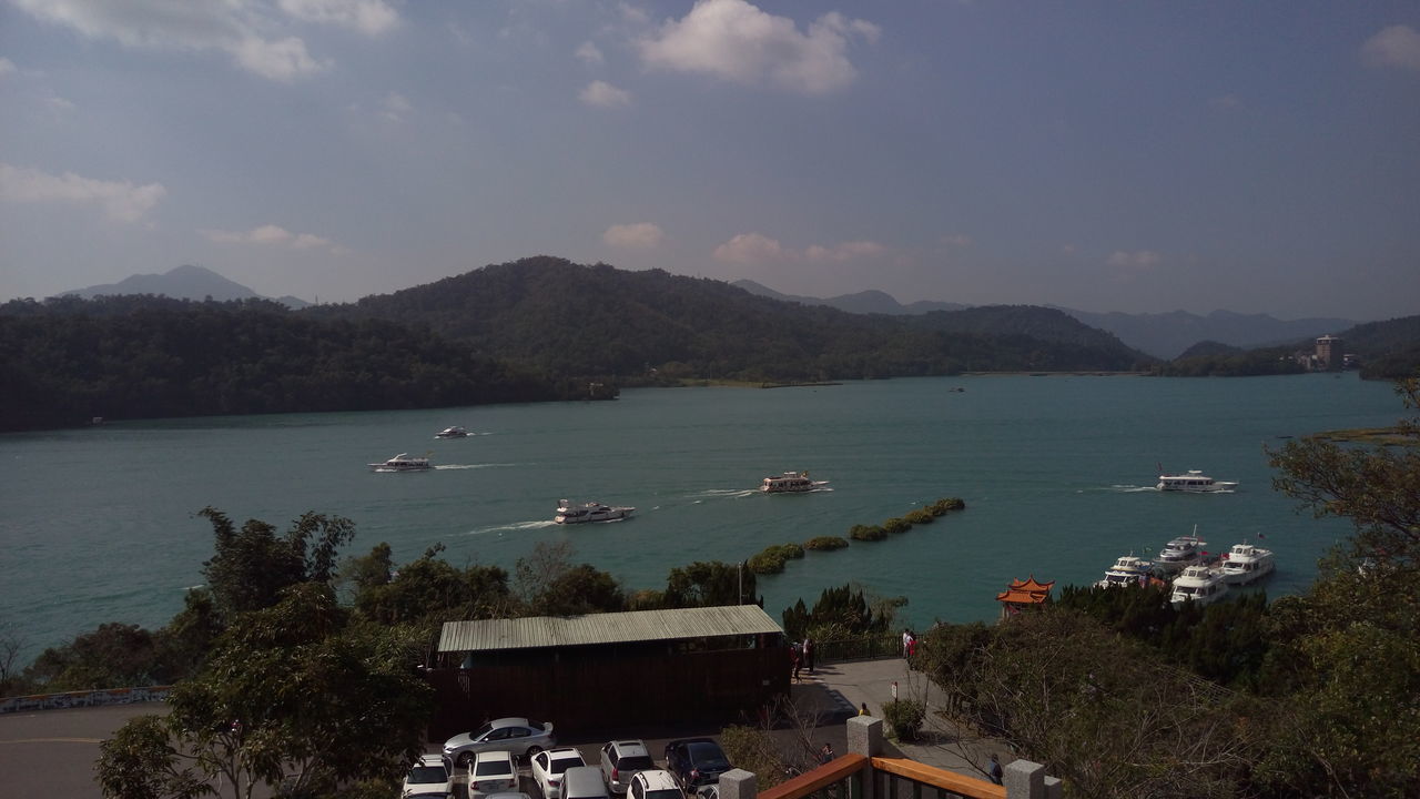 HIGH ANGLE VIEW OF BOATS MOORED ON SEA BY MOUNTAINS AGAINST SKY