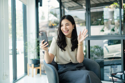 Portrait of young woman using mobile phone in cafe