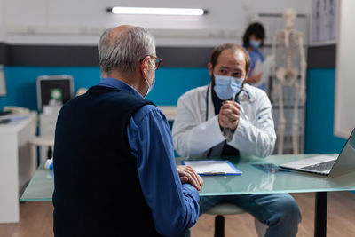 Doctor wearing mask talking with patient in clinic