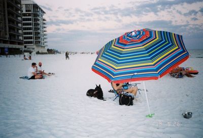 People at beach against sky in city