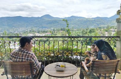 Parents with son sitting in balcony against landscape