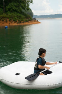 Rear view of man sitting on boat in lake