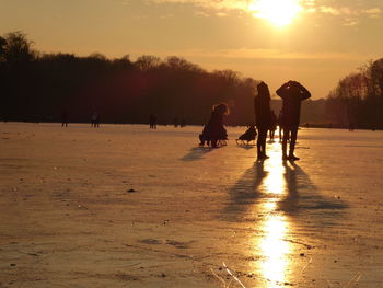 People on frozen lake during sunset