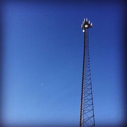 Low angle view of electricity pylon against clear blue sky