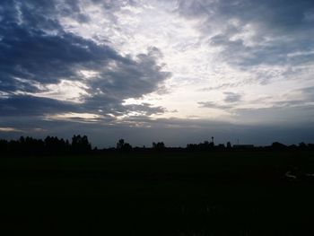 Silhouette trees on field against sky at sunset