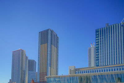 Low angle view of modern buildings against clear blue sky