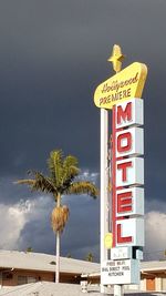 Information sign by palm trees against sky