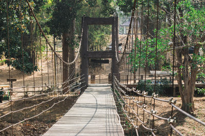 Empty footbridge amidst trees in forest