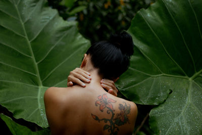Rear view of woman with green leaves