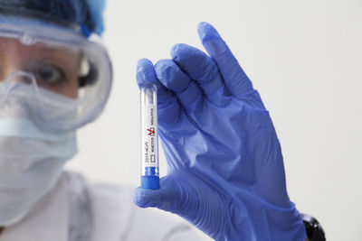 Close-up of scientist holding test tube against white background