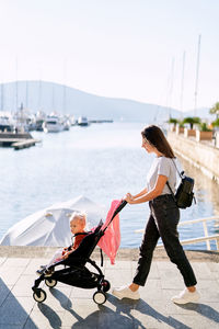 Women with umbrella on shore against sky