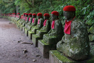 Old statues in row against plants