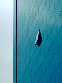 Low angle view of glass building against blue sky