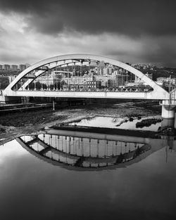 Bridge over river in city against sky