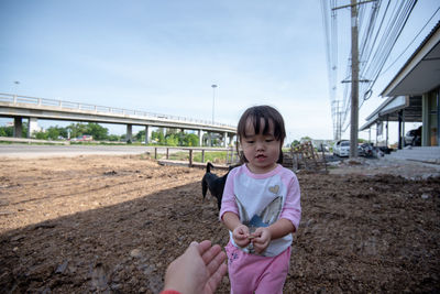 Cropped hand of parent gesturing towards daughter standing on field against sly