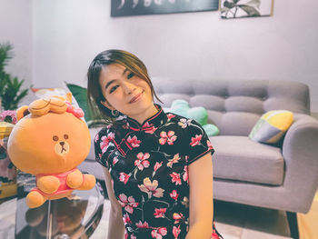 Smiling woman with stuffed toy at home