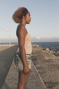 Profile view of thoughtful young woman standing on promenade against sky