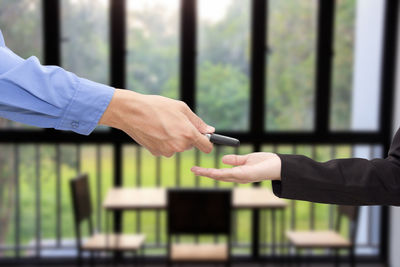 Cropped hand of man giving key to woman