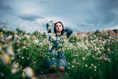 Young woman standing on field against sky