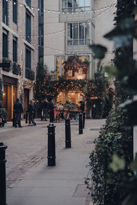 People walking on sidewalk by buildings in city