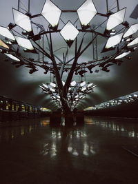 Illuminated tree by bridge against sky at night