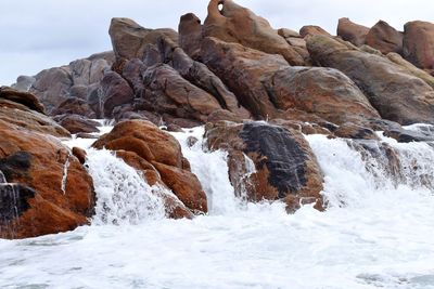 Rocks in water against sky